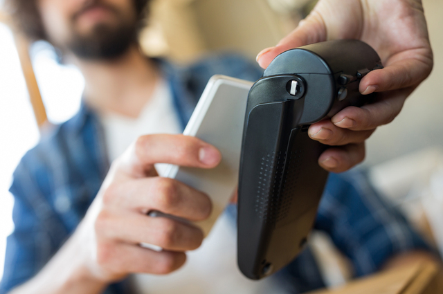 Man paying with NFC technology on mobile phone